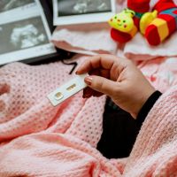 Hand holding a positive pregnancy test